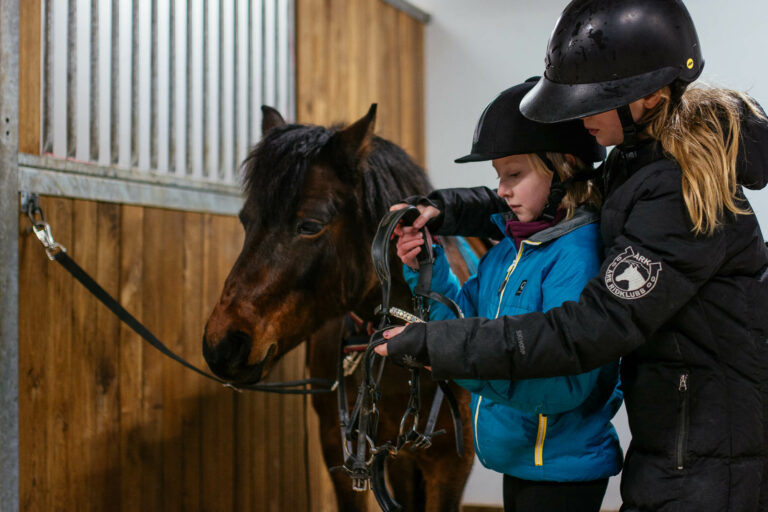 Stallvärd hjälper barn att tränsa ponny